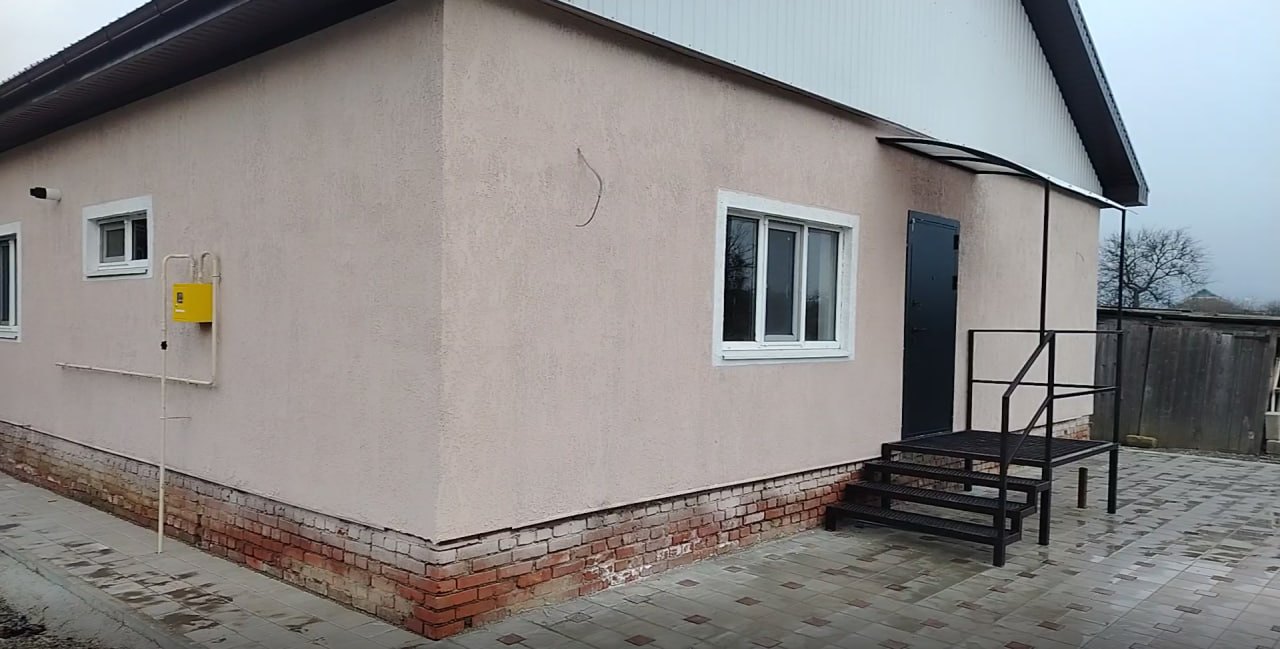 Одноэтажный дом с оштукатуренным фасадом и металлическим крыльцом